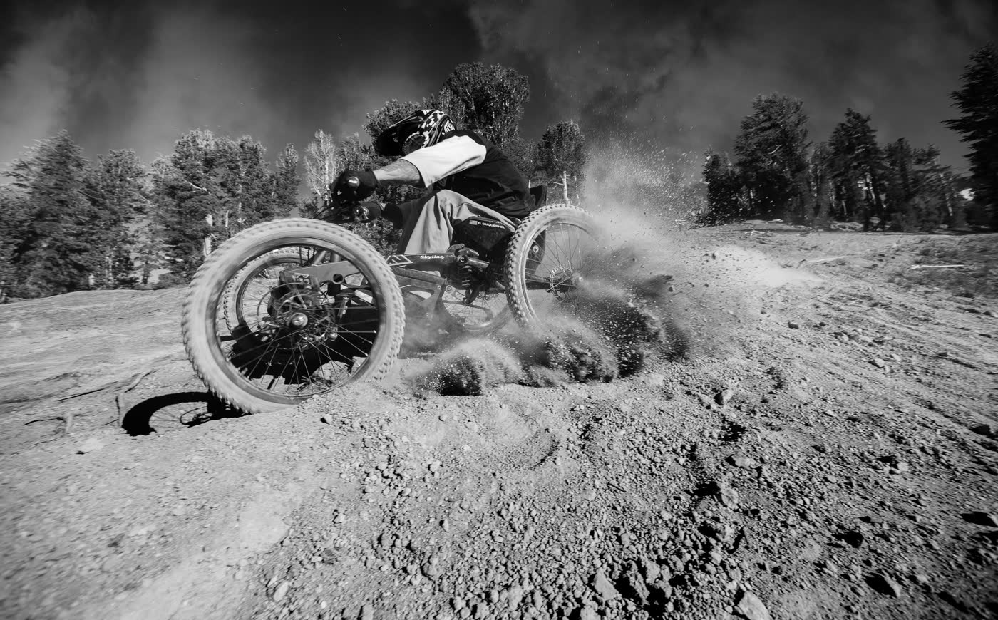 Black and white photograph of an adaptive mountain bike sliding through dirt
